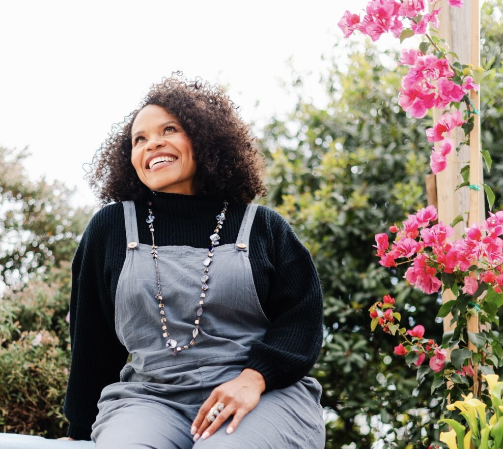 Image of woman wearing silver jewelry and overalls in nature