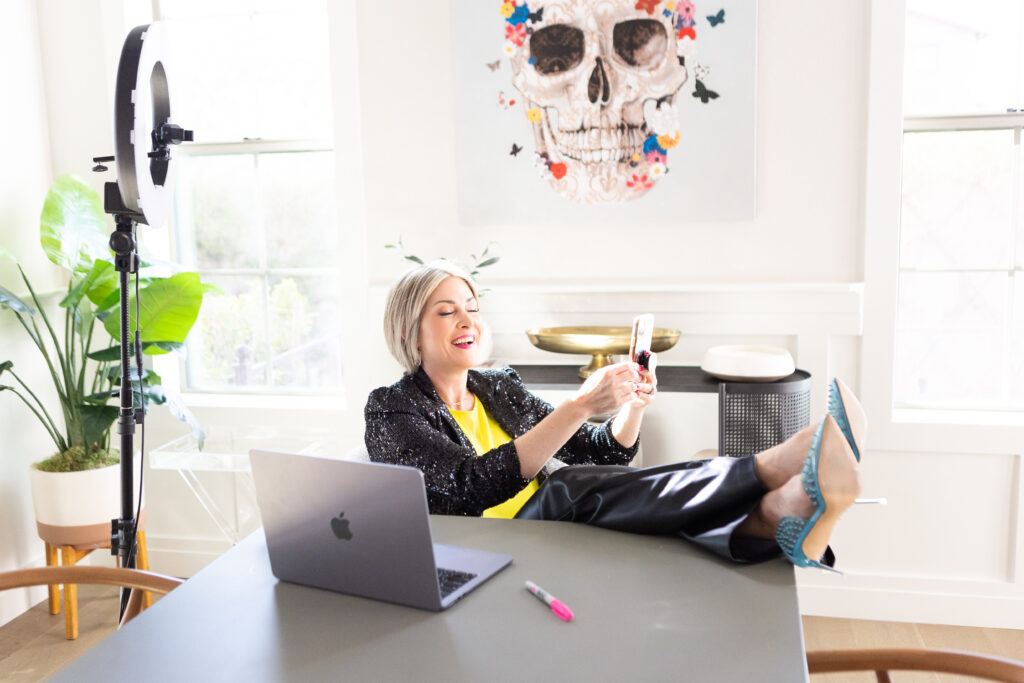 lady with short hair kicking her feet up in blue pumps holding her phone instead of doing work on her computer branding shoot ROI