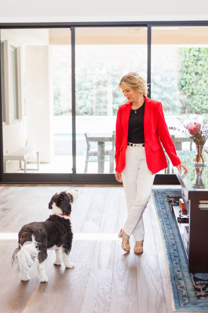 woman in red blazer looking at her dog with short hair and black shirt and white pants branding shoot ROI