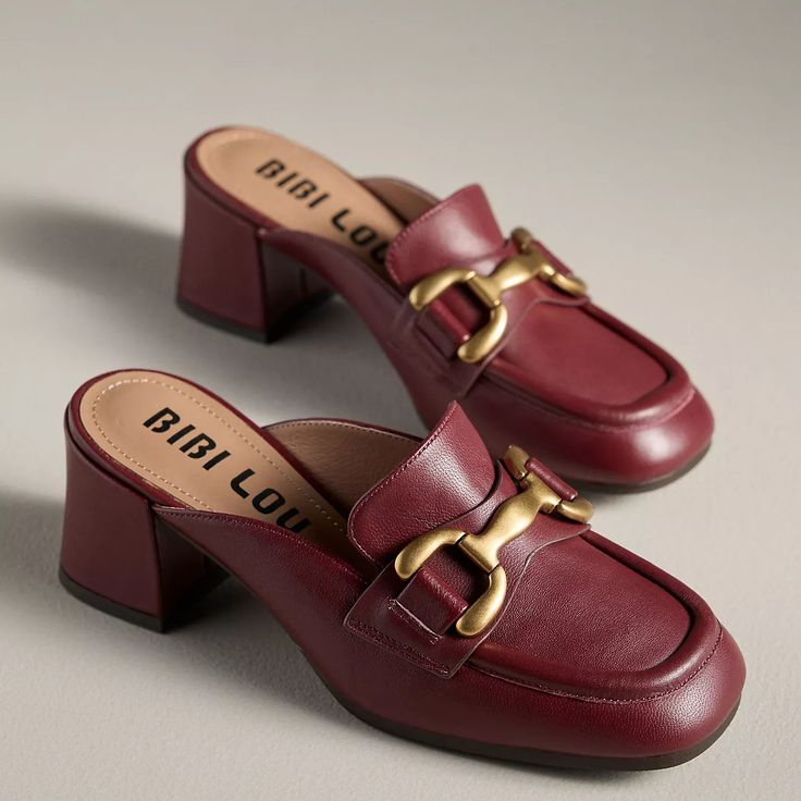 A pair of maroon Bibi Lou mule loafers with gold bit detailing and block heels are displayed on a neutral background.