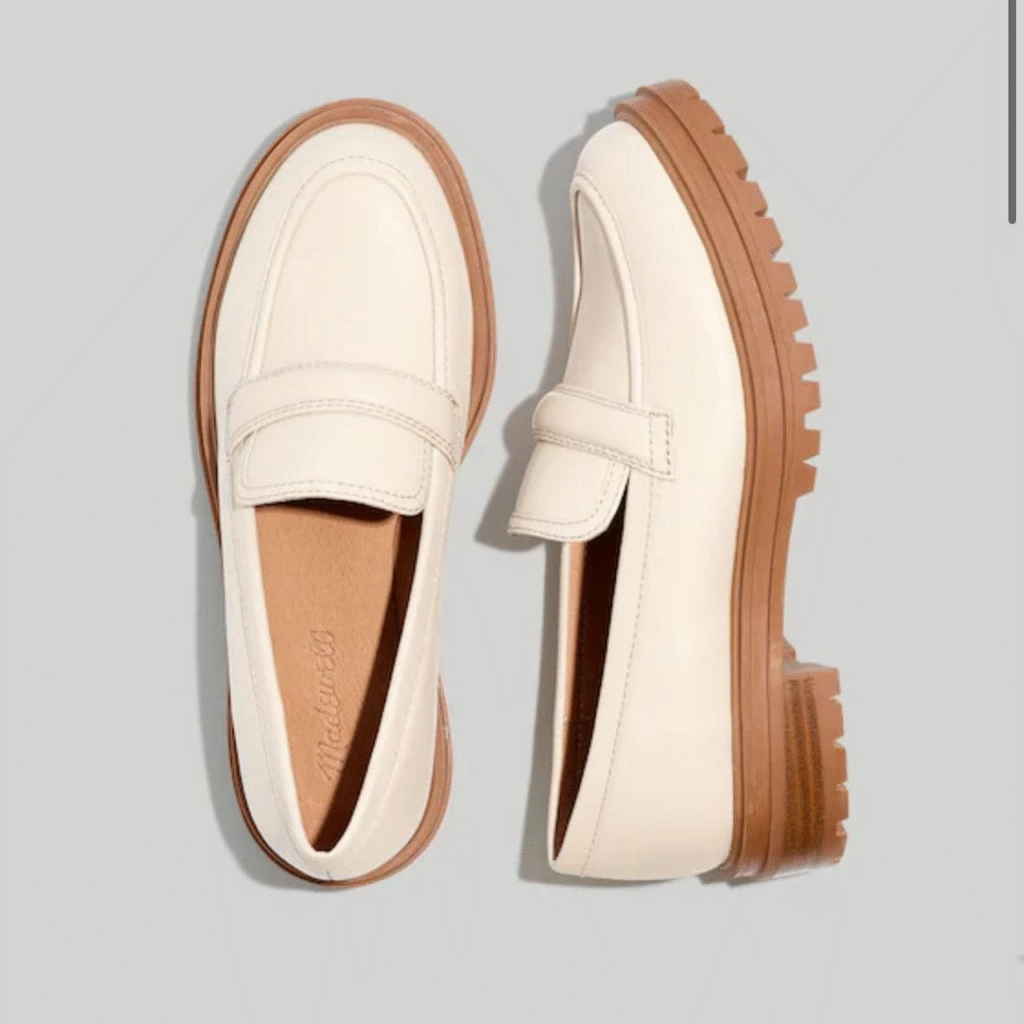 A pair of cream-colored leather loafers with tan soles and a chunky lug sole on the right shoe.